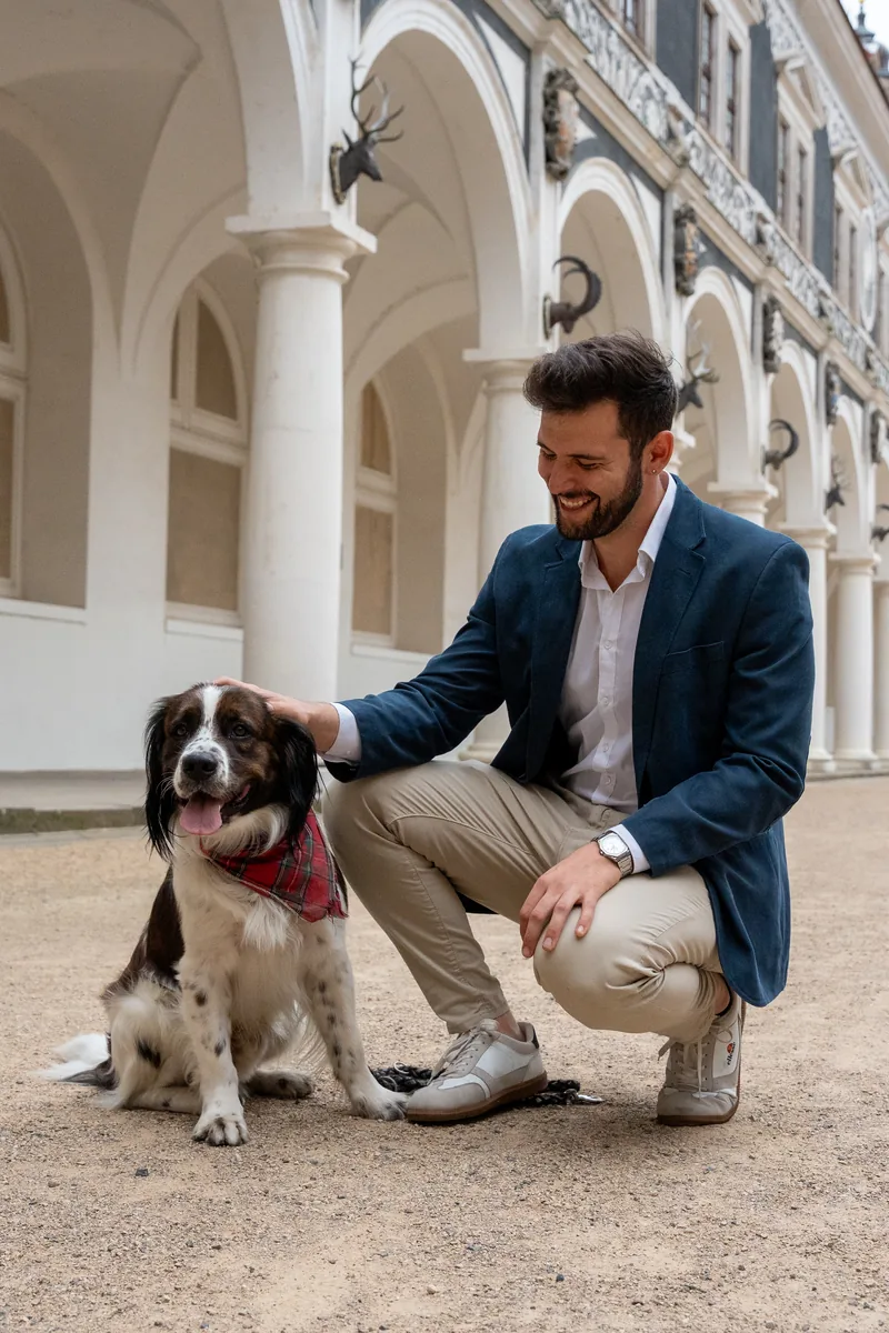 Julio Bernal com um cachorro sob as arcadas de um pátio histórico em Dresden